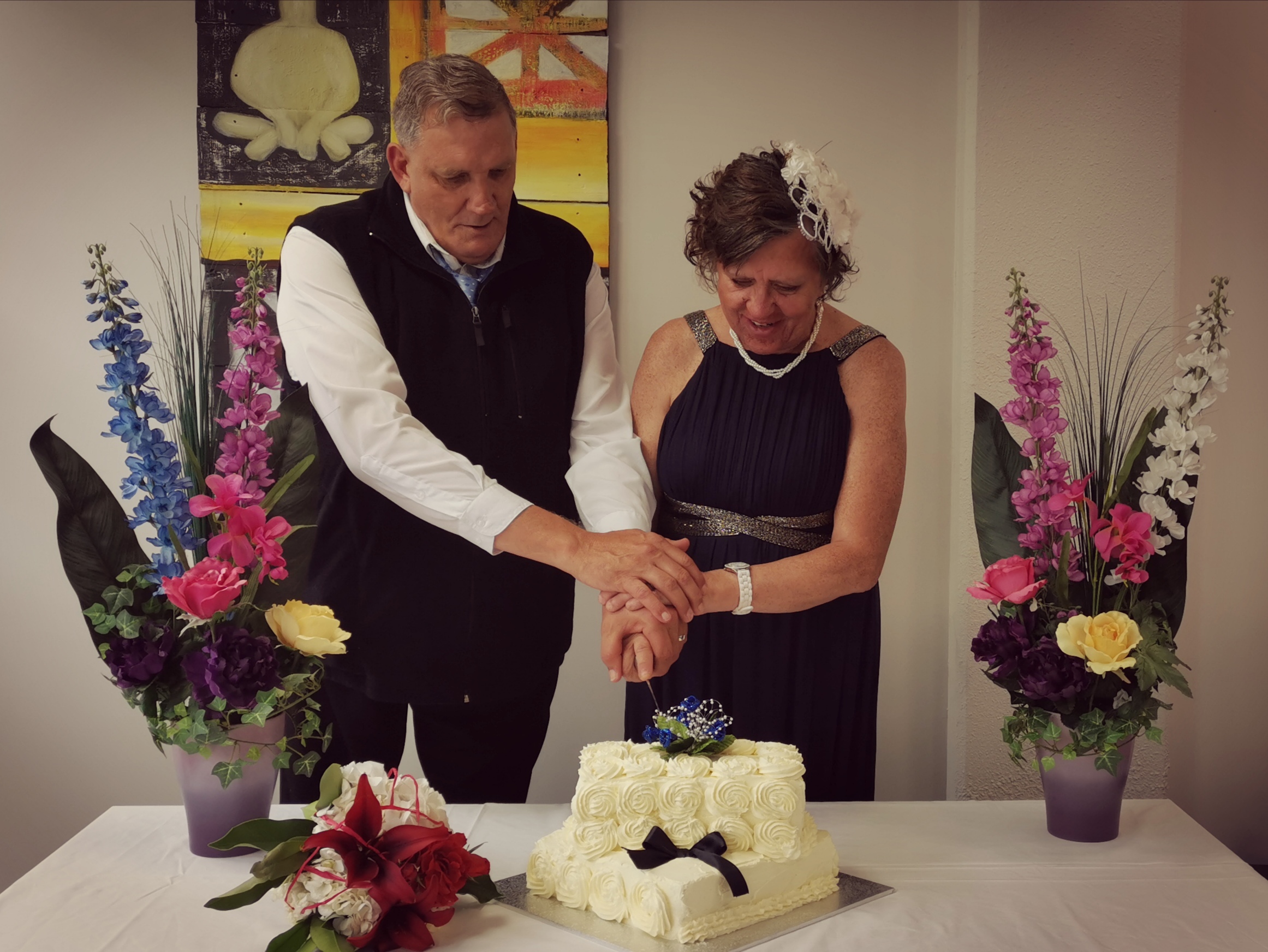 Paul (left) and Pip (right) both holding a knife cutting their cake